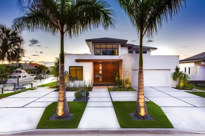 beach house in white simple landscaping ideas two tall palm trees in front of it tiled pathways with small flower beds in front of large wooden front door