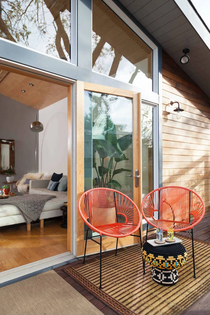 black table ottoman next to two orange metal chairs in front of bedroom door wooden floor small backyard landscaping ideas
