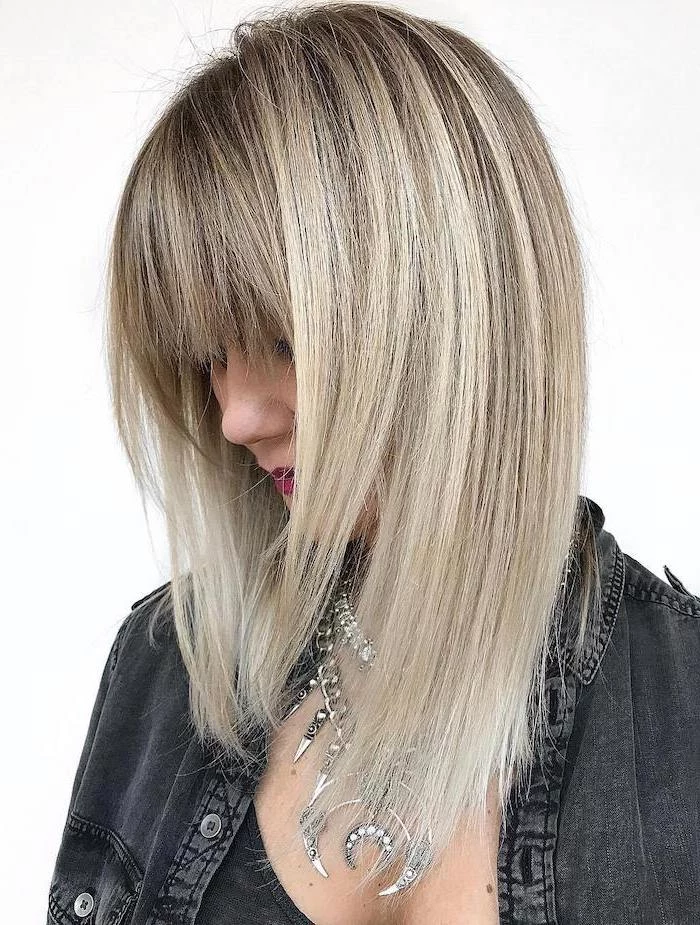 blonde hair with bangs and blonde highlights hairstyles for medium hair woman wearing black denim shirt lots of silver necklaces