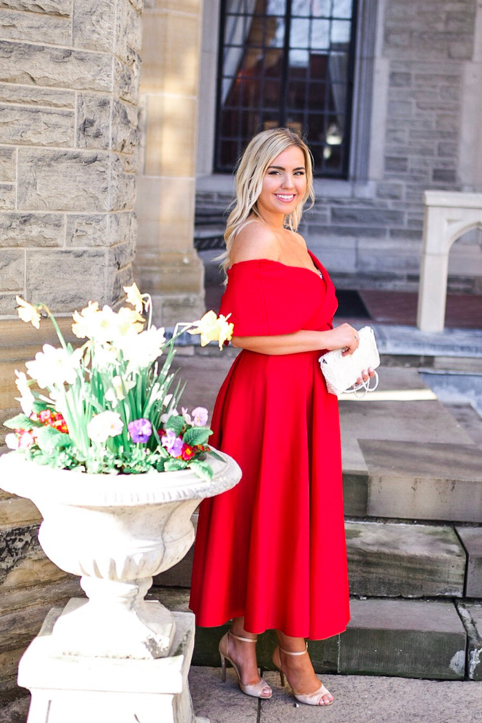blonde woman wearing red strapless dress standing on staircase formal dresses for weddings wearing white shoes and bag