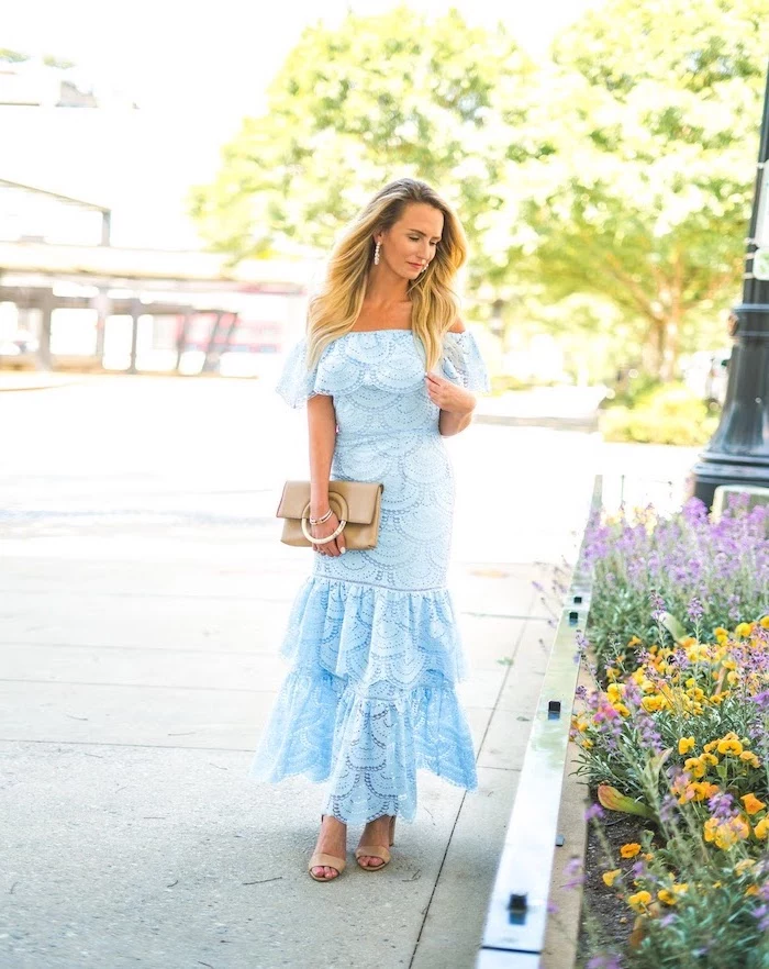 blonde woman with long wavy hair beautiful dresses to wear to a wedding wearing blue lace strapless dress nude sandals leather bag