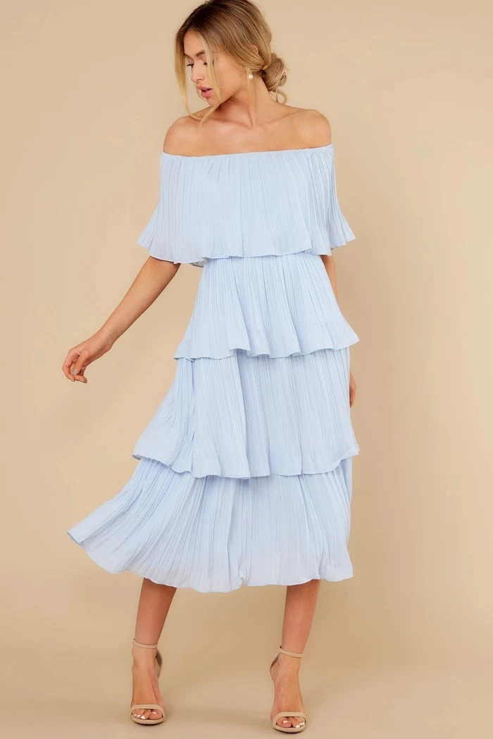 blonde woman with low updo cocktail dresses for weddings wearing strapless blue pleated midi dress nude sandals