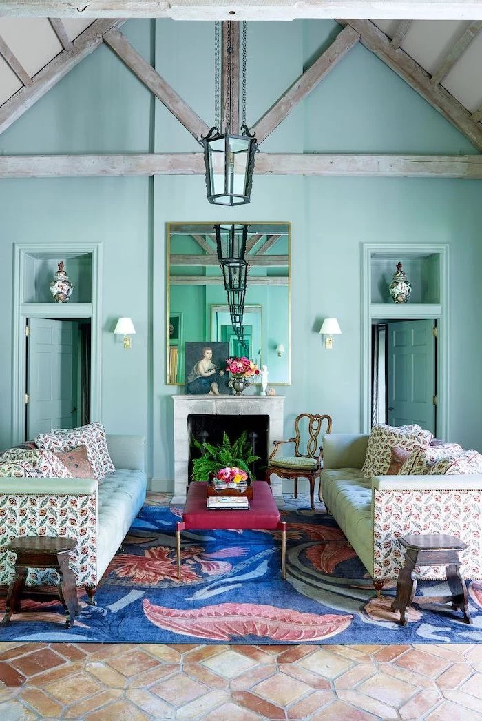 blue carpet on tiled floor neutral color palette mint green walls cathedral ceiling with exposed wood beams mint green sofas in front of fireplace