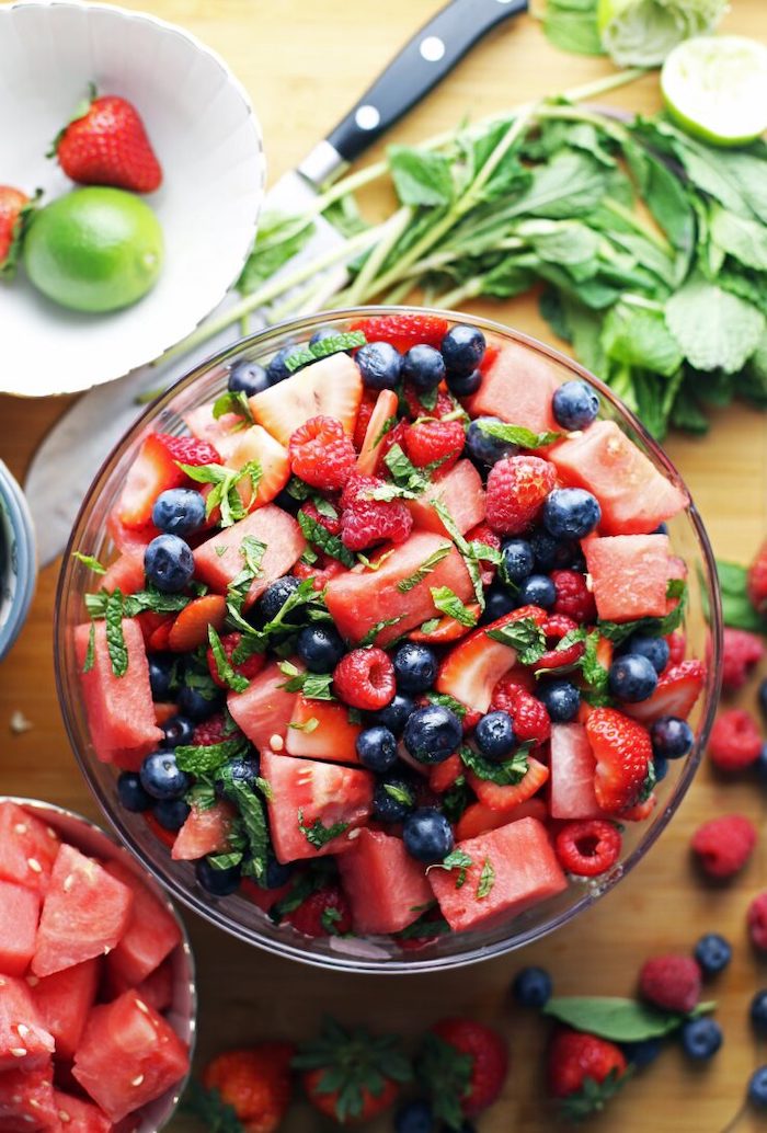 blueberries raspberries watermelon strawberries chopped mint leaves inside glass bowl healthy salad recipes wooden table