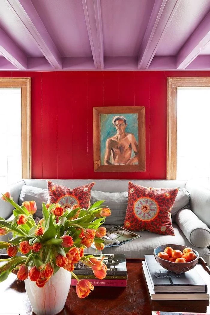 books on wooden table in front of grey sofa with red throw pillows living room wall colors wooden wall in red wooden ceiling in purple