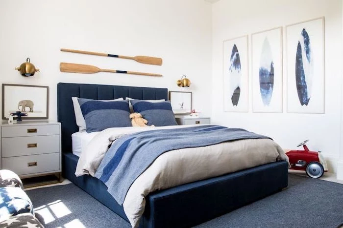 boys room paint ideas sailing theme two paddles hanging above dark blue velvet bed with white and blue bed sheets three posters on white wall