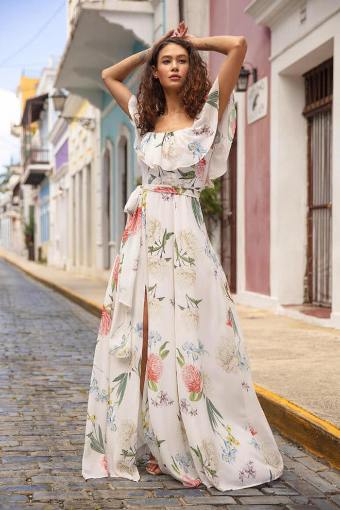 brunette woman with curly hair wearing long white dress with white blue and orange flowers beach dresses