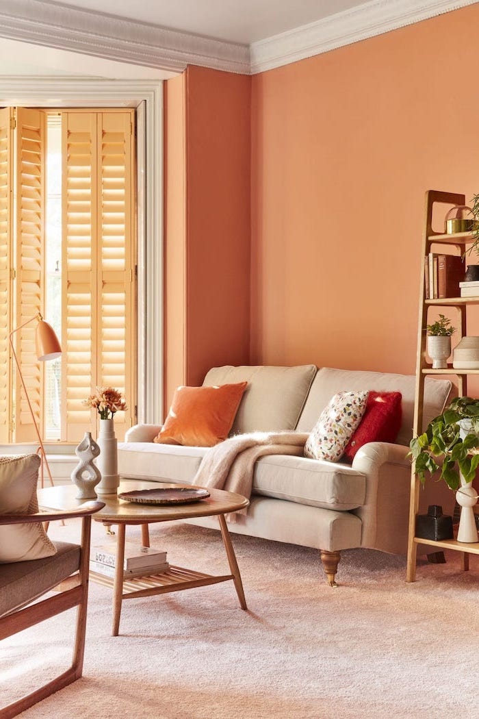 coral wall white sofa with orange and red throw pillows colors that go with grey wooden bookshelf coffee table armchair