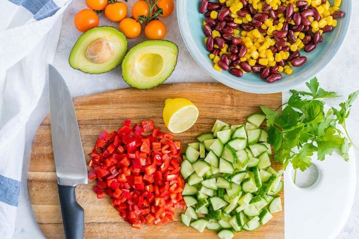 cucumbers peppers chopped on wooden cutting board salads for a crowd bowl with corn and beans