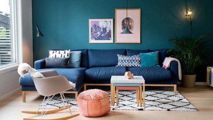 dark blue corner sofa turquoise wall with wall art interior paint colors white and black carpet on wooden floor orange ottoman