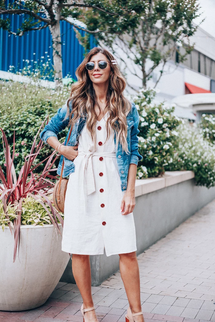 denim jacket on top of white dress worn by woman with long wavy hair cotton summer dresses beige sandals bag