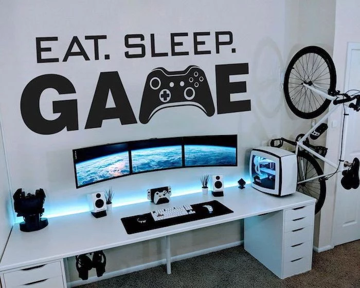 eat sleep game sticker on white wall white wooden desk teen boy room ideas gaming setup with three monitors bike on the side