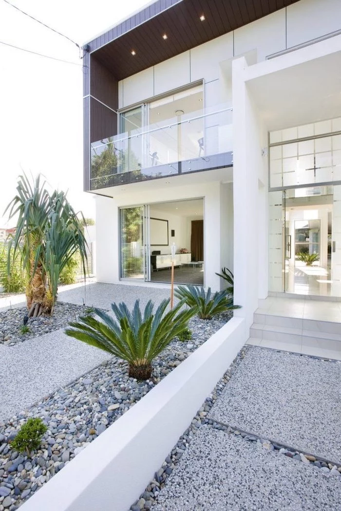 facade of two storey house front yard landscaping ideas tiled gravel pathway leading to the front door palm trees planted in the gravel