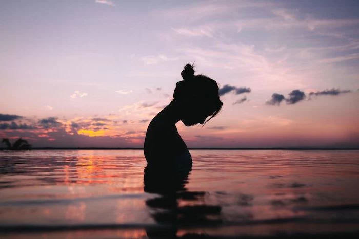 female silhouette at sunset cute aesthetic wallpapers woman standing in the water with hair in a bun