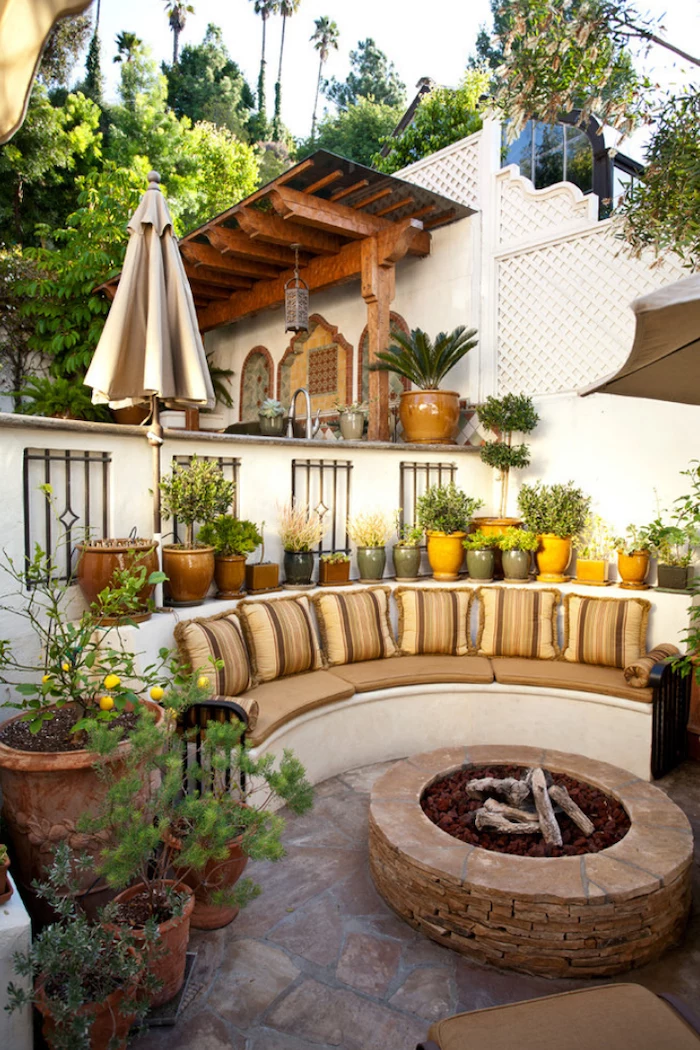 fireplace made of bricks surrounded by sofa with beige cushions backyard landscaping ideas stone floor lots of plants