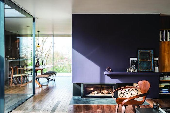 fireplace on purple wall room paint colors wooden armchair wooden floor tall windows open plan kitchen living room