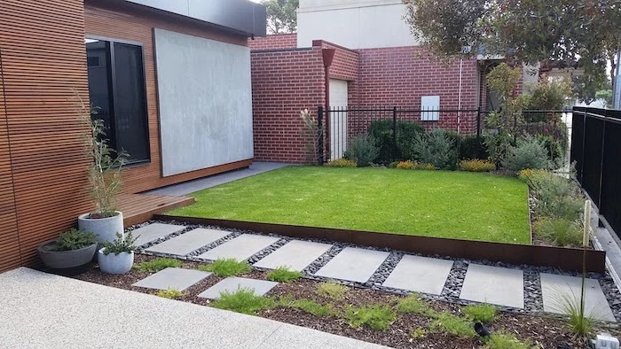 front of house landscaping pathway between gate and front door tiles in gravel with bushes and grass around