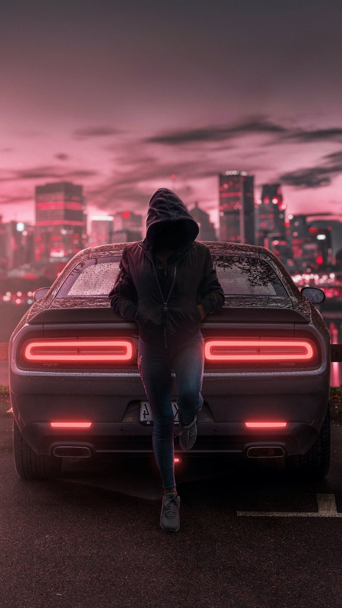 girl wearing jeans and black hoodie leaning on dodge challenger wallpapers for guys city skyline in the background