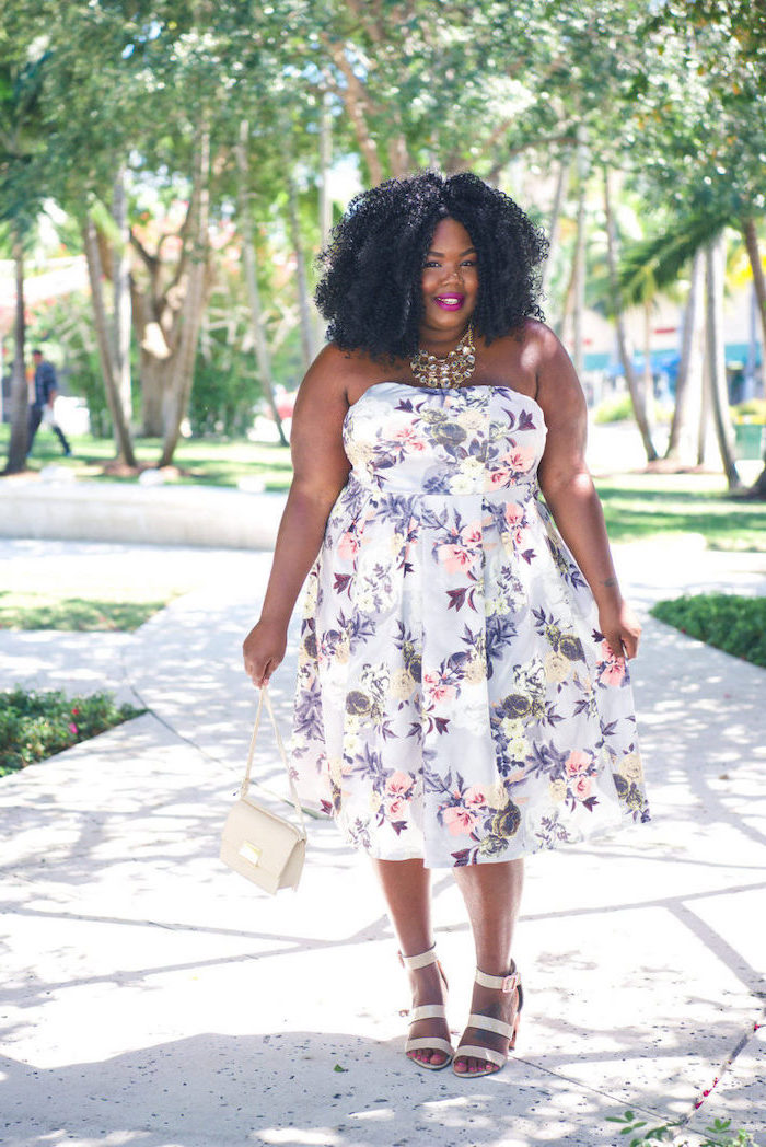 girl with black curly hair cocktail dresses for weddings wearing strapless white midi dress with purple white pink flowers white sandals bag