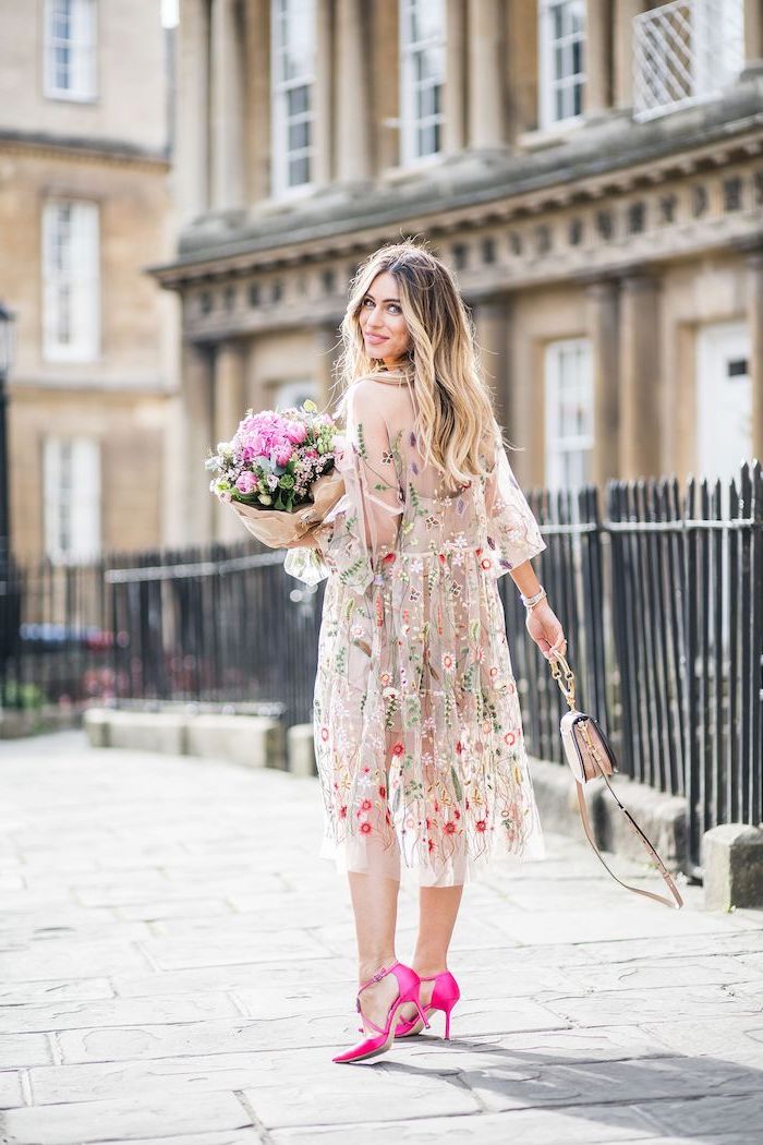 girl with long wavy balayage hair beach wedding guest dresses wearing nude tulle dress with flowers pink shoes holding a bouquet of flowers