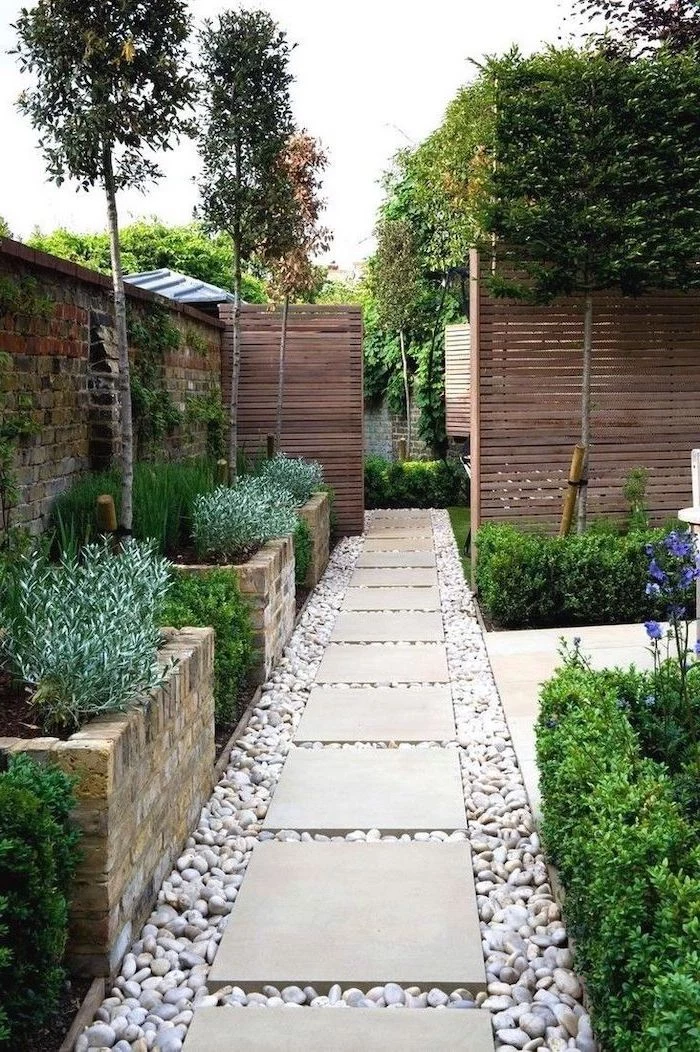 gravel pathway with white tiles small front yard ideas surrounded by flower beds and bushes and trees