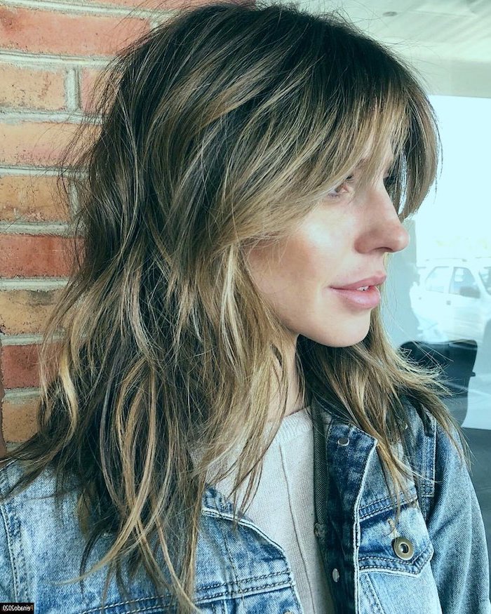 haircuts for thin hair woman with brunette hair with blonde highlights with bangs wearing denim jacket