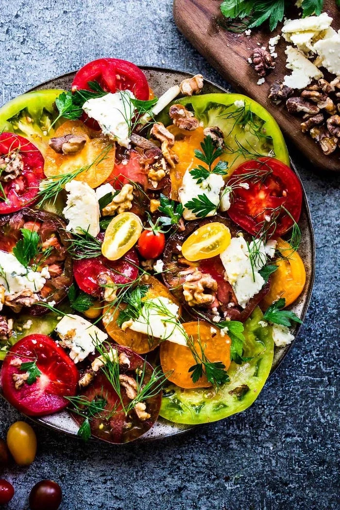 heirloom tomatoes with dill walnuts feta cheese summer salads placed on dark surface