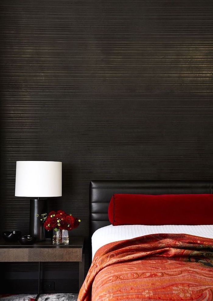 how to decorate a bedroom black wall black leather bed frame red blanket red velvet throw pillows dark wooden night stand