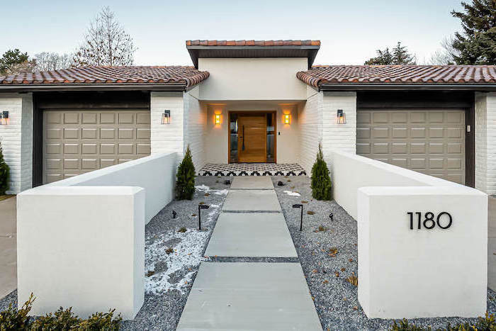 large tiles leading to the front door surrounded bt gravel with small bushes planted small front yard ideas white brick wall