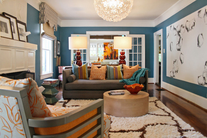 living room color schemes walls painted in blue white carpet on wooden floor grey sofa with orange throw pillows orange armchair in front of fireplace