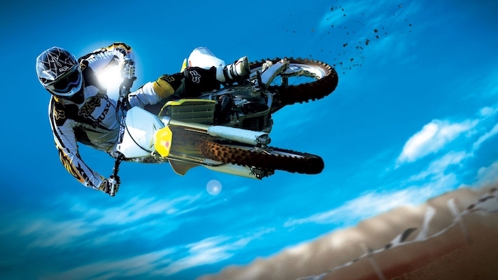 man wearing a helmet jumpin in the air with motorcycle blue sky in the background cool wallpaper hd