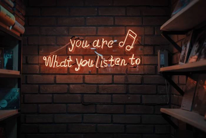 neon sign on brick wall next to wooden bookshelves cute wallpapers for girls you are what you listen to
