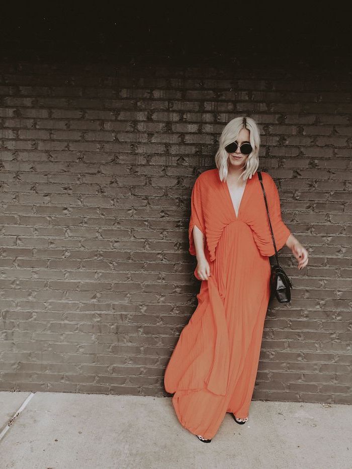 orange long pleated dress worn by woman with short wavy blonde hair long sleeve wedding guest dresses black sandals and leather crossbody bag