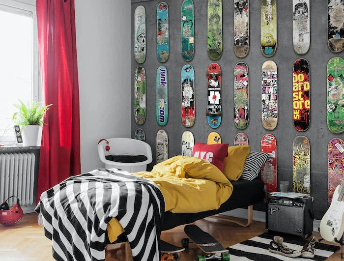skateboard shaped metal plaques arranged hanging on grey wall behind the bed boys bedroom furniture wooden floor with guitar stand and two skateboards