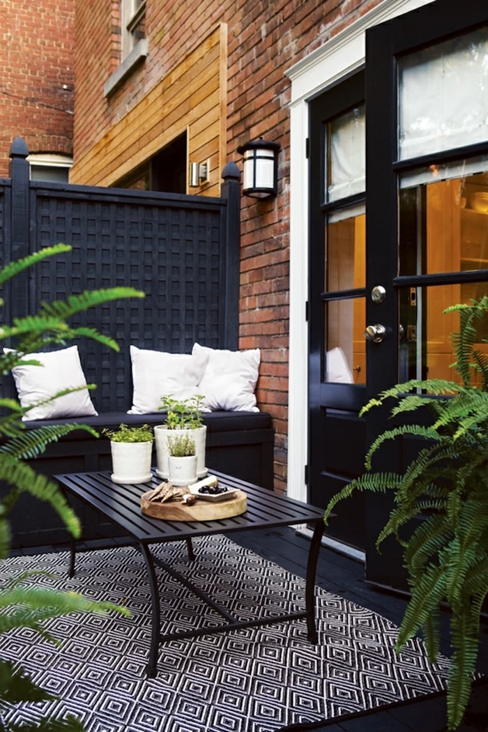 small apartment balcony enclosed patio ideas black bench metal coffee table wooden floor and door white throw pillows