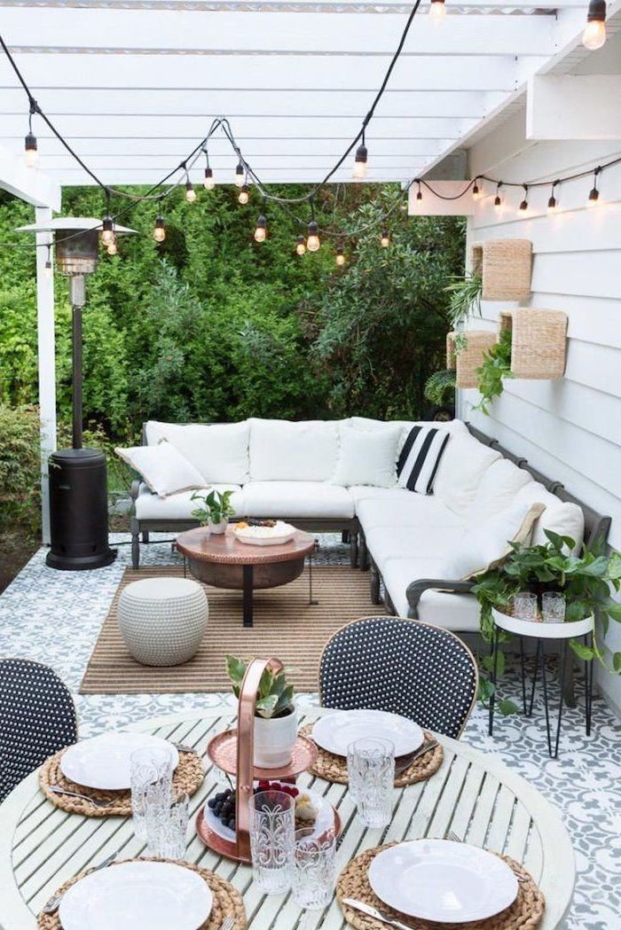 strings of lights under white wooden pergola garden furniture set with white cushions backyard landscaping ideas wooden dining table