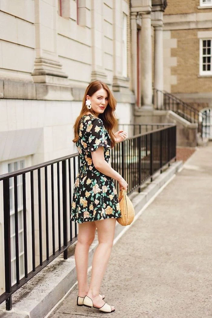 summer maxi dresses woman with ginger hair wearing black dress with yellow orange flowers standing on the sidewalk