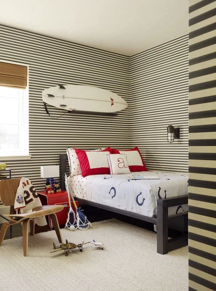 teen boy bedroom furniture surf hanging on the wall above the bed walls in black and white stripes lacrosse gear on wooden chair