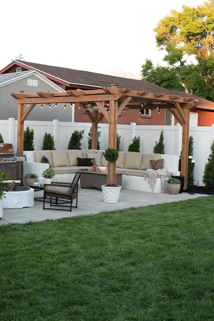 tiled floor concrete patio ideas garden furniture set with beige cushions next to grill station under wooden pergola with strings of lights