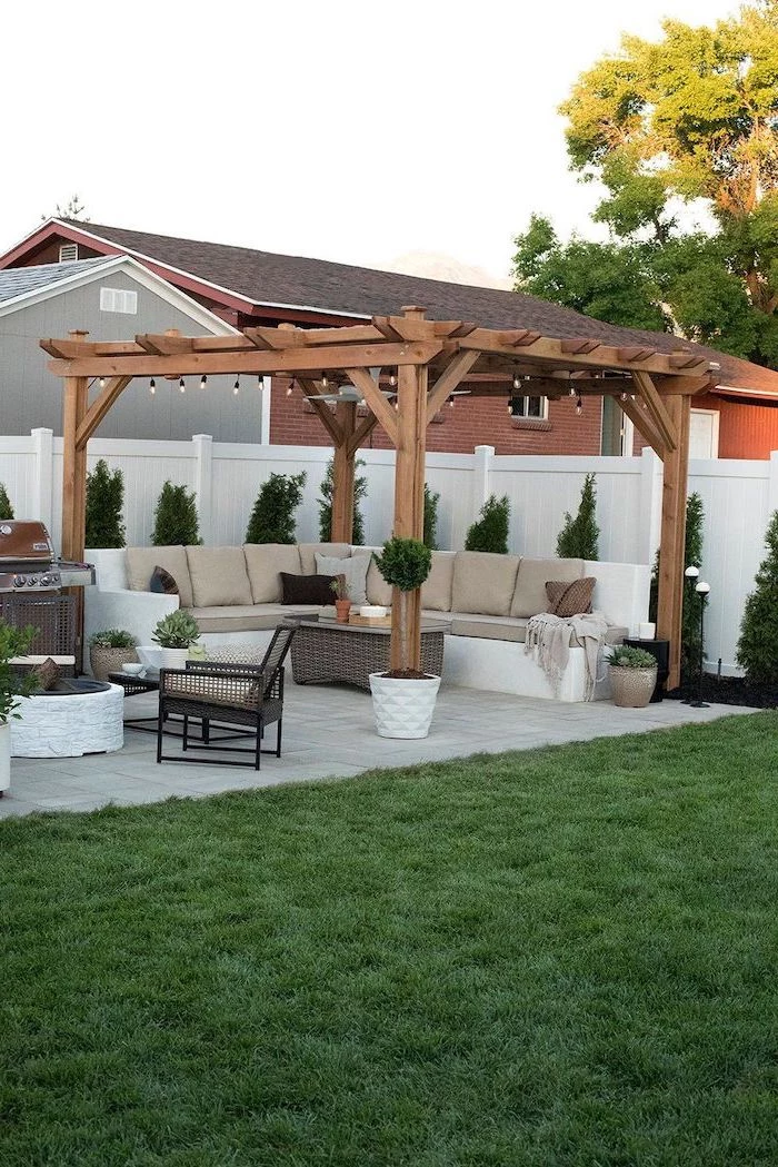 tiled floor concrete patio ideas garden furniture set with beige cushions next to grill station under wooden pergola with strings of lights