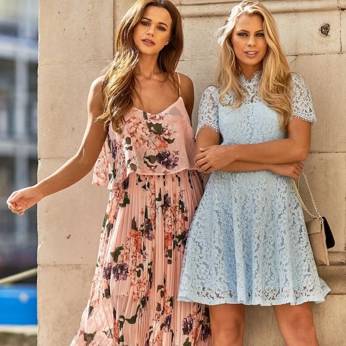 two women with blonde wavy hair beach wedding guest dresses one wearing pink pleated dress with flowers other wearing blue lace dress
