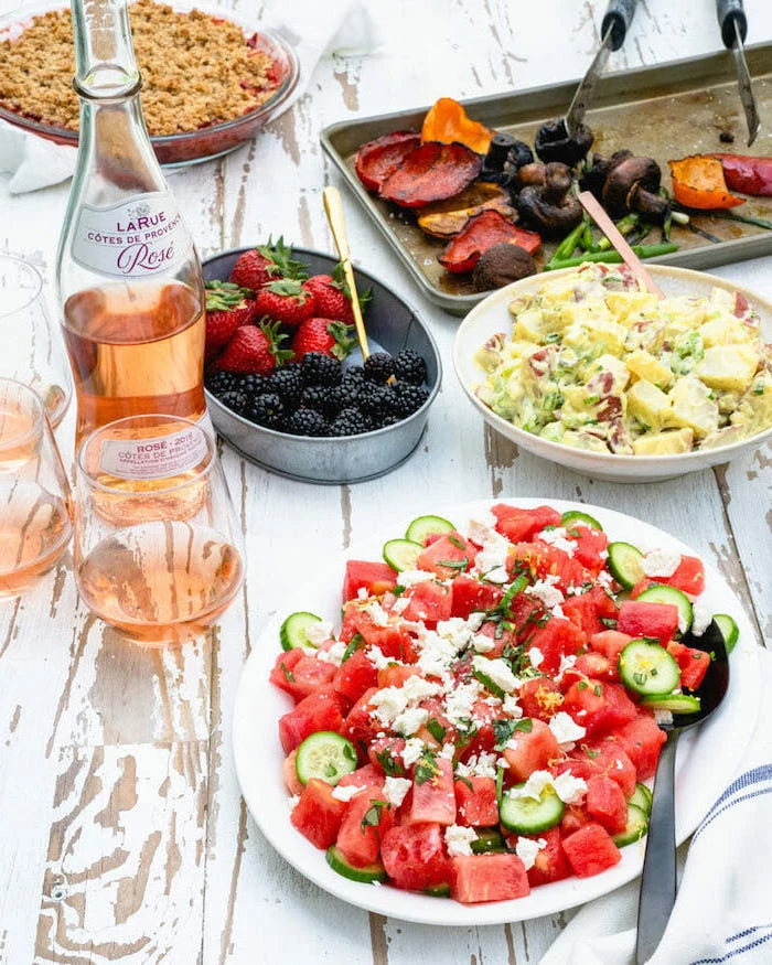 watermelon cucumber feta cheese salad in white plate healthy salad recipes rose bottle on white wooden table