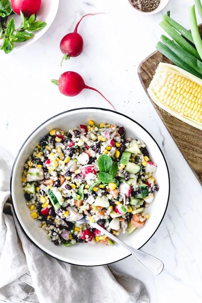 white metal bowl filled with corn salad with black beans summer salad recipes cucumbers onion fresh mint leaves on top
