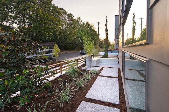 white tiles on the side of a house front yard landscaping ideas with rocks bushes and small trees planted next to it