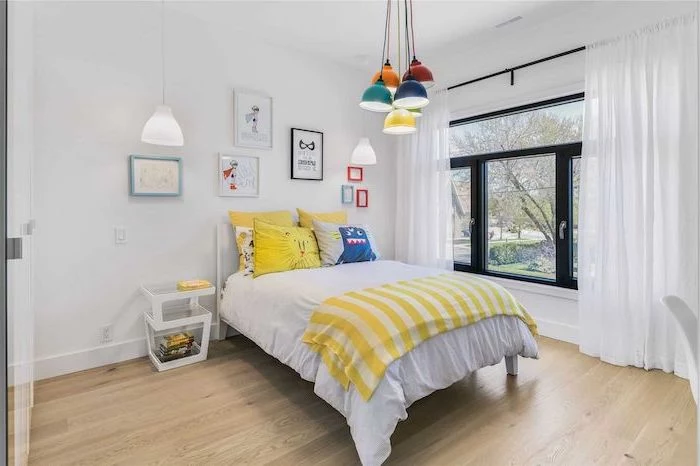 white walls wooden floor large window with white curtains teen boy bedroom furniture colorful lamps hanging from the ceiling