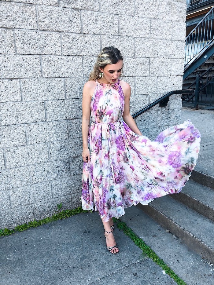 woman with balayage hair wearing midi white dress with purple flowers wedding guest dresses standing on staircase