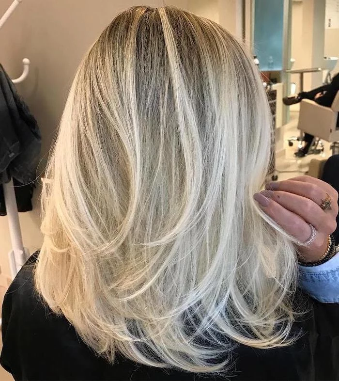 woman with blonde hair with blonde highlights hairstyles for medium hair long nails with beige nail polish