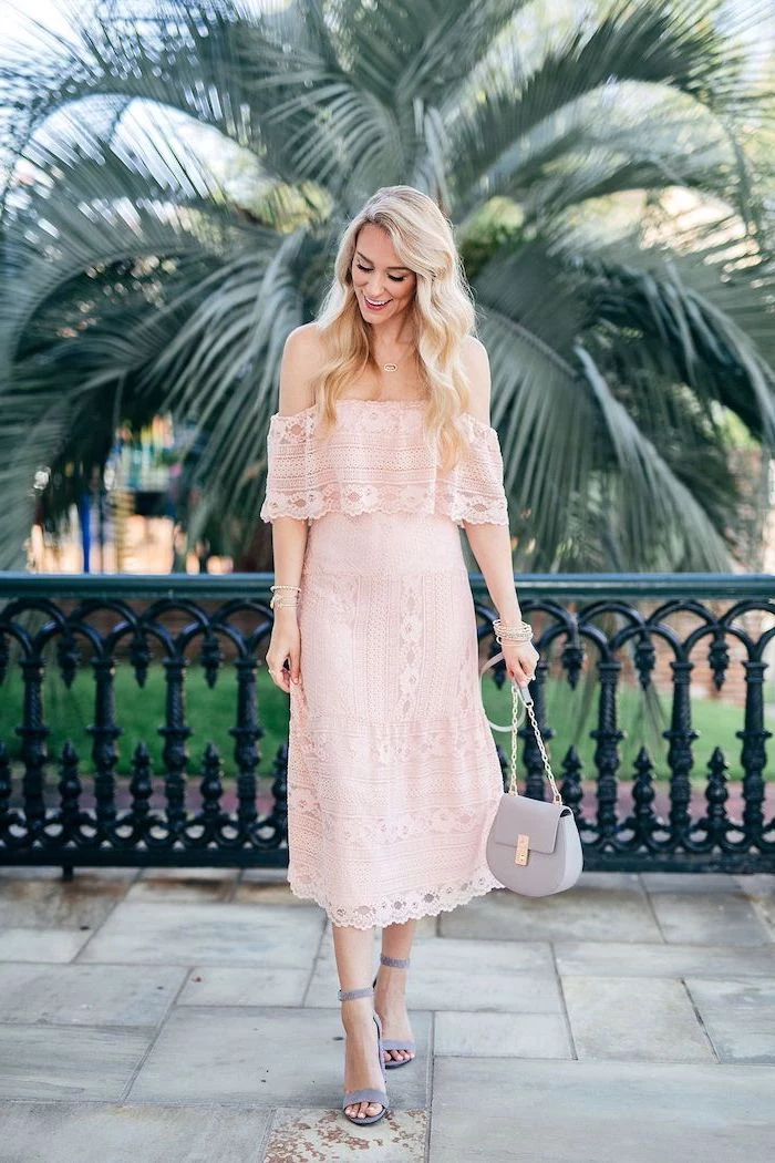 woman with long blonde wavy hair wedding guest dresses wearing strapless pink lace dress grey sandals leather bag