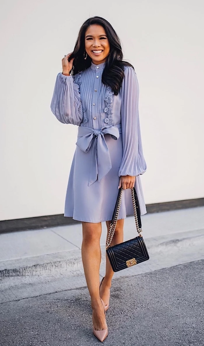 woman with wavy black hair wearing shirt purple dress with long pleated sleeves nude shoes black leather bag dresses to wear to a summer wedding
