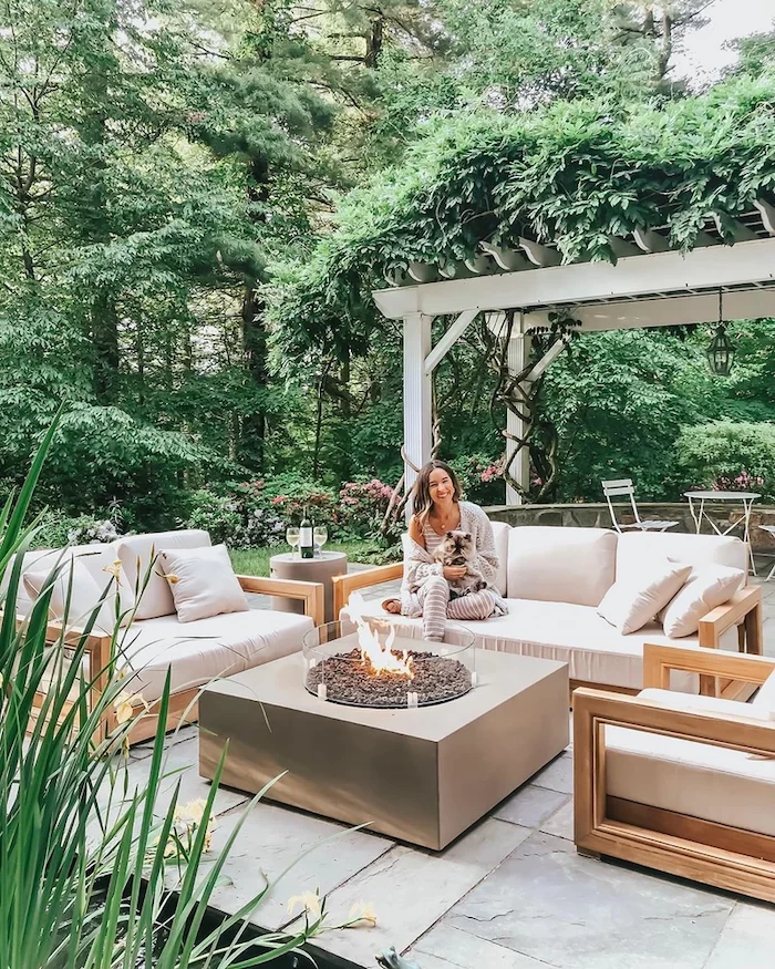 wooden garden furniture set with white cushions arranged around fire pit concrete patio ideas stone tiled floor